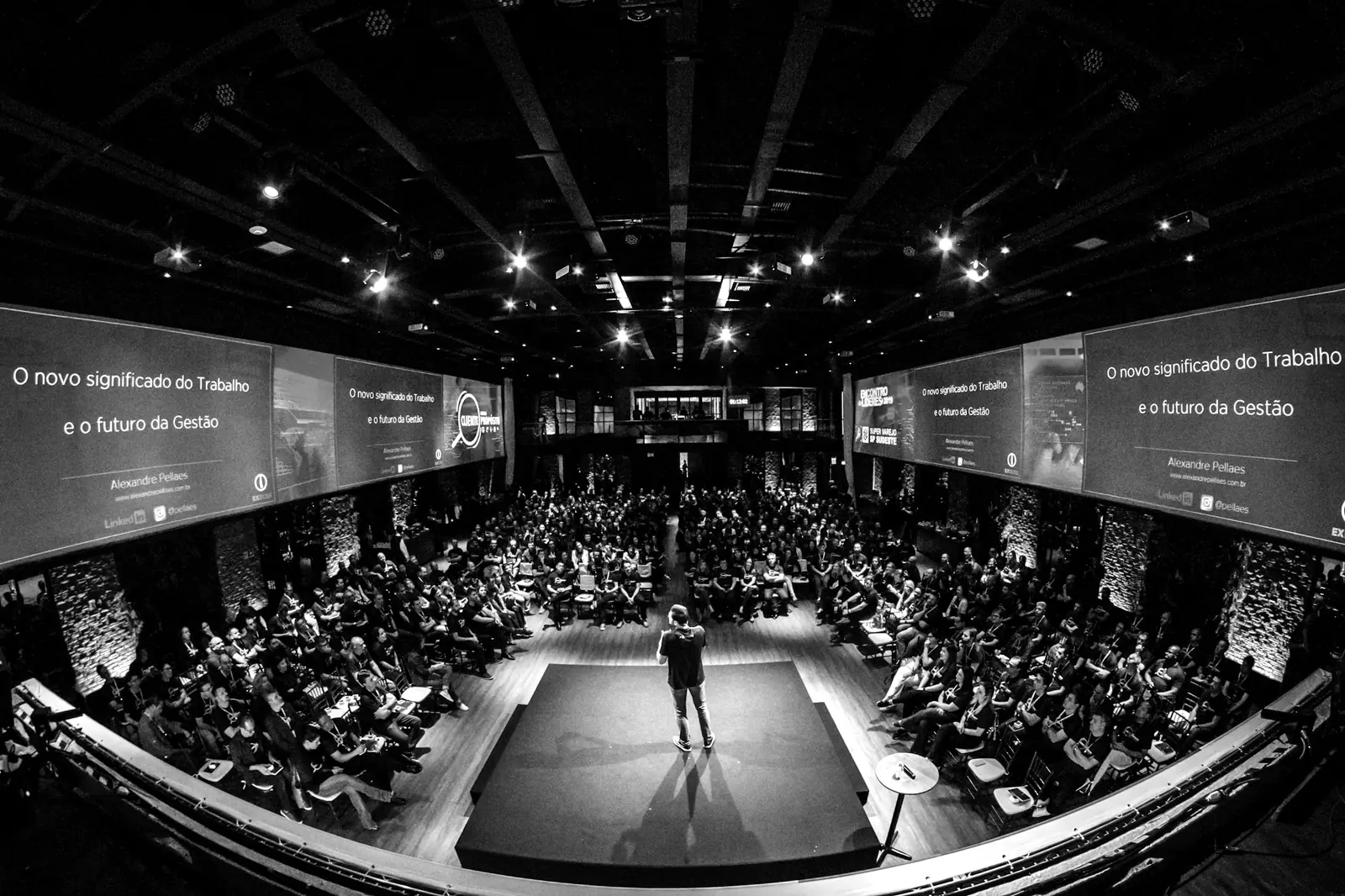 Une grande salle de convention, scène éclairée et public